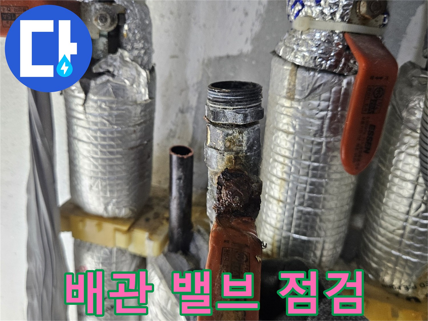 주황색 손잡이가 달린 배관 밸브와 보온재 마감 상태입니다.