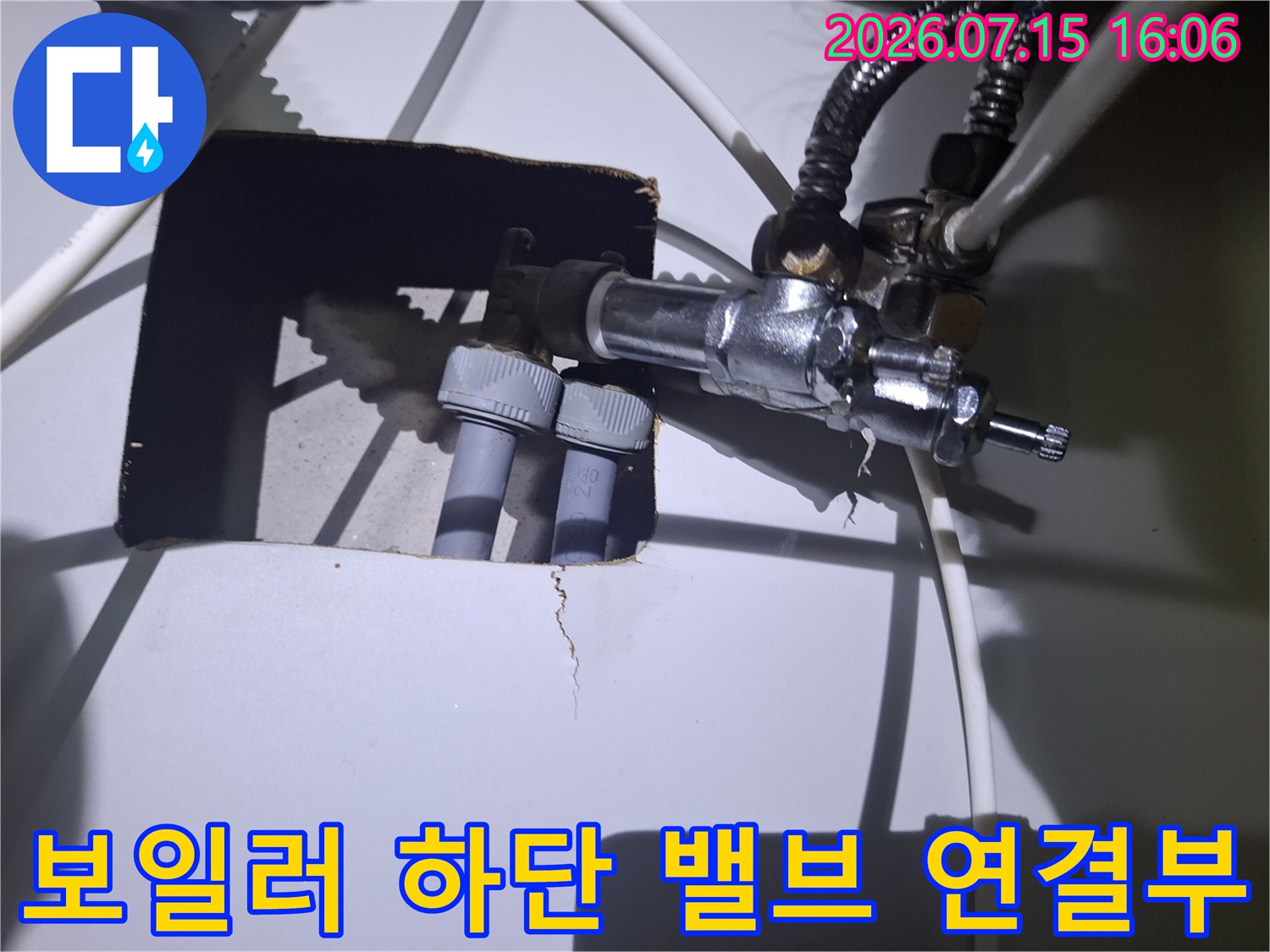 회색 플라스틱 배관과 금속 밸브가 결합된 보일러 하부의 상세한 모습