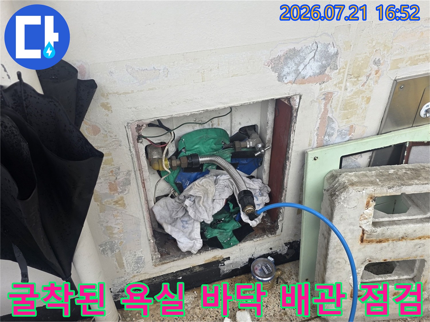 노출된 파란색 호스형 배관과 주변 콘크리트 벽면의 방수 처리를 진행하는 공사 현장
