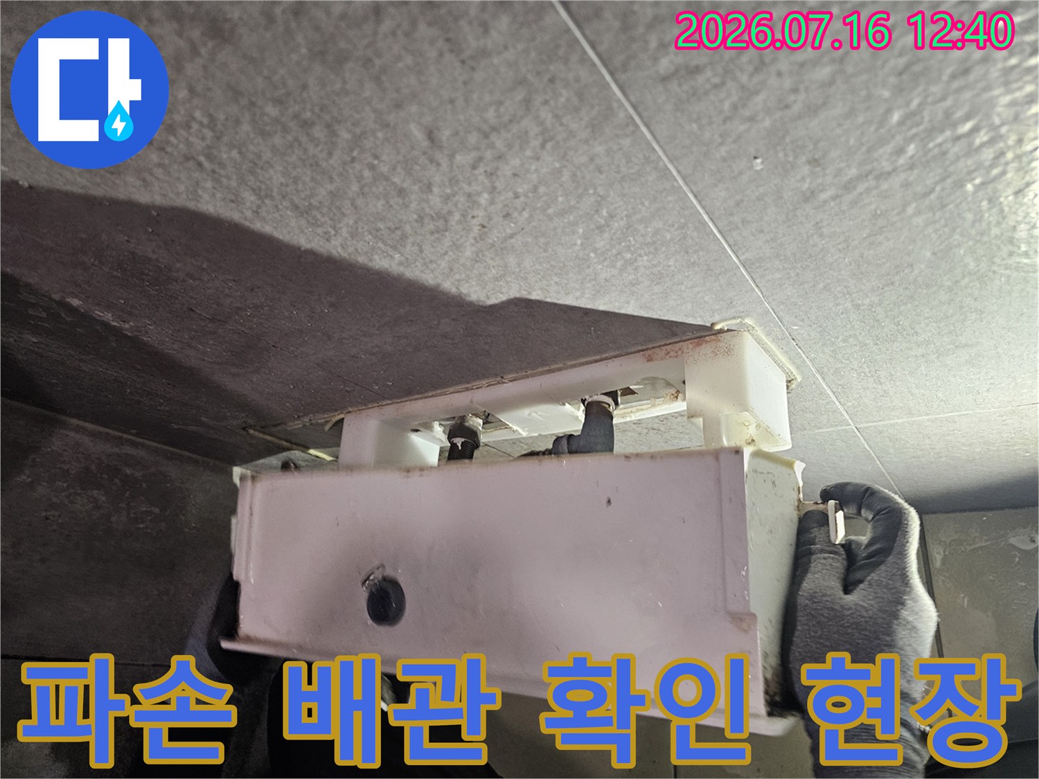 작업자가 장갑을 끼고 노출된 수도 배관의 연결 부위를 세밀하게 점검하는 모습