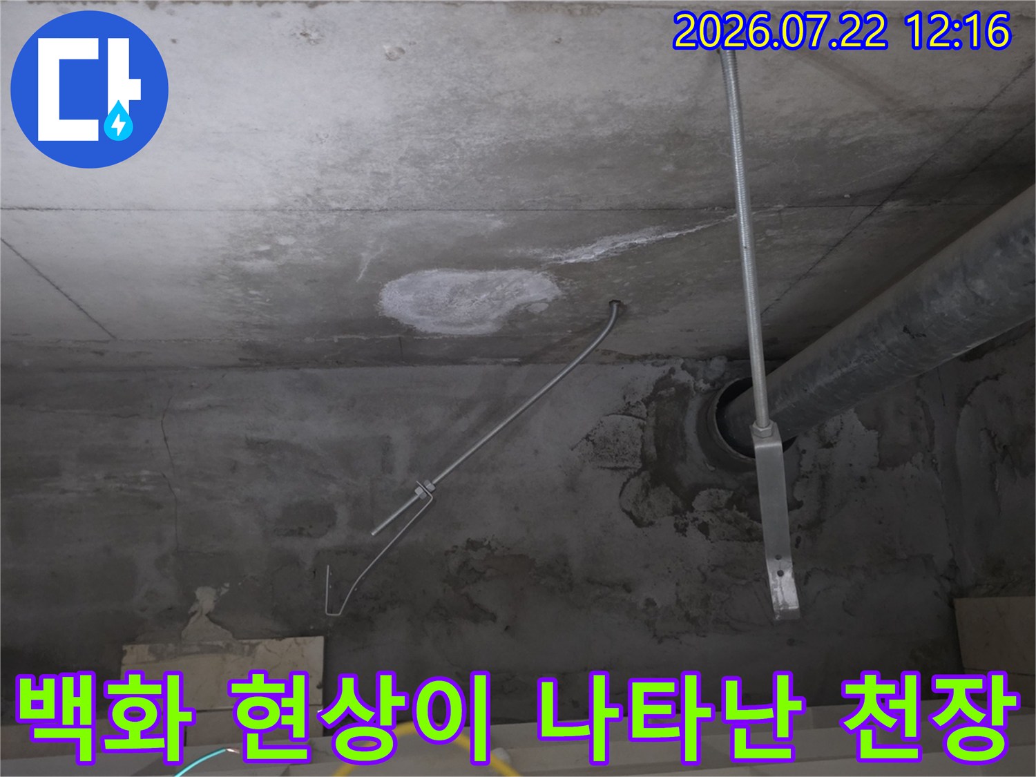 회색 콘크리트 천장의 배관 틈새로 하얀 석회질의 백화 현상이 발생한 장면