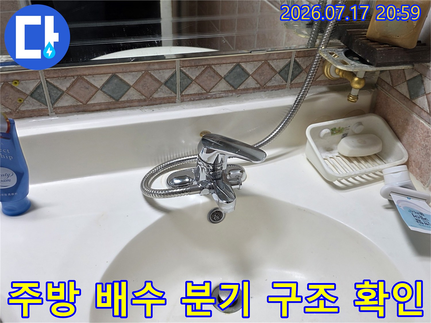 싱크대 아래 복잡한 배출 경로와 연결 부위를 세밀하게 관찰하는 장면입니다.