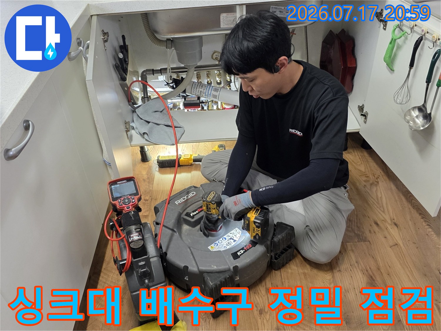 싱크대 하부 공간에서 탐지 기기를 통해 배출 경로의 누수를 파악하는 모습