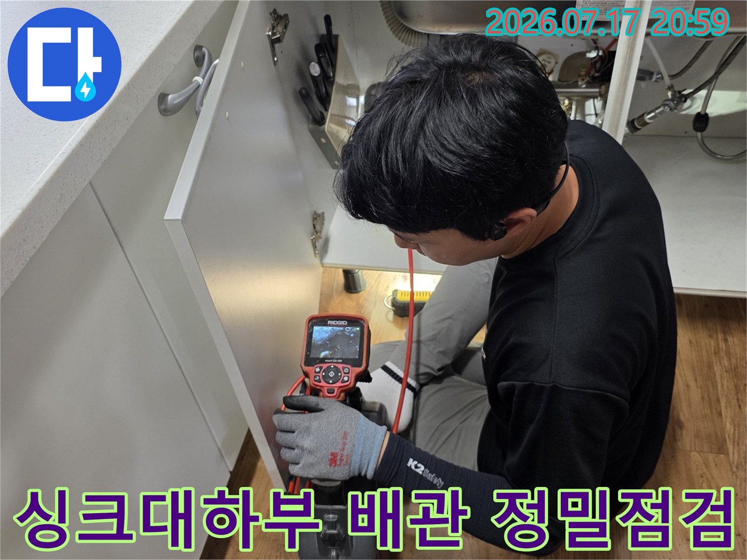 엔지니어가 싱크대 아래에서 장비를 활용해 매립된 느낌의 배관을 세밀하게 점검하는 현장 사진