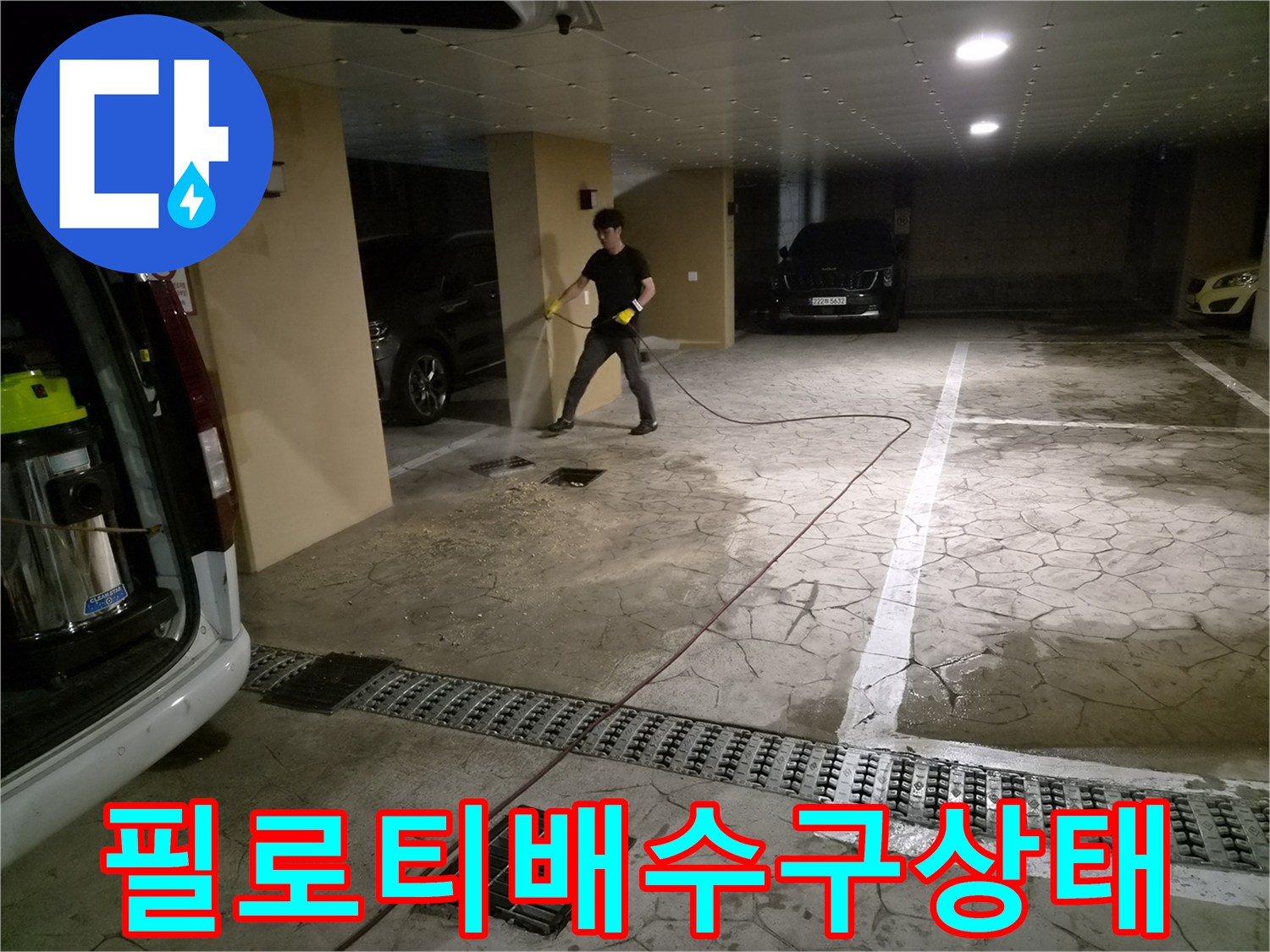 물이 고여 있는 주차장 바닥과 점검을 수행 중인 작업자