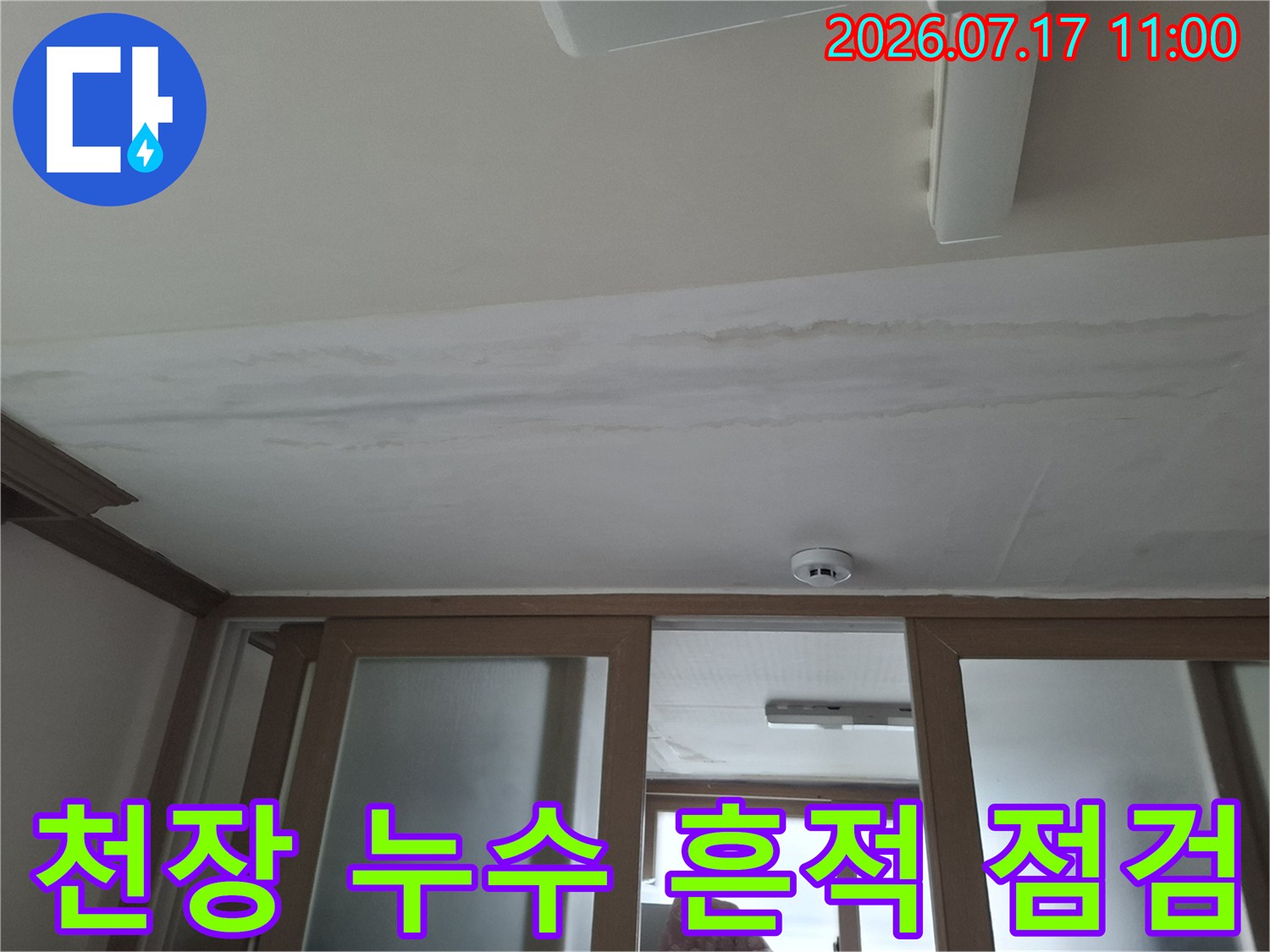 흰색 천장 마감재에 물이 스며든 자국과 화재 감지기가 설치된 모습