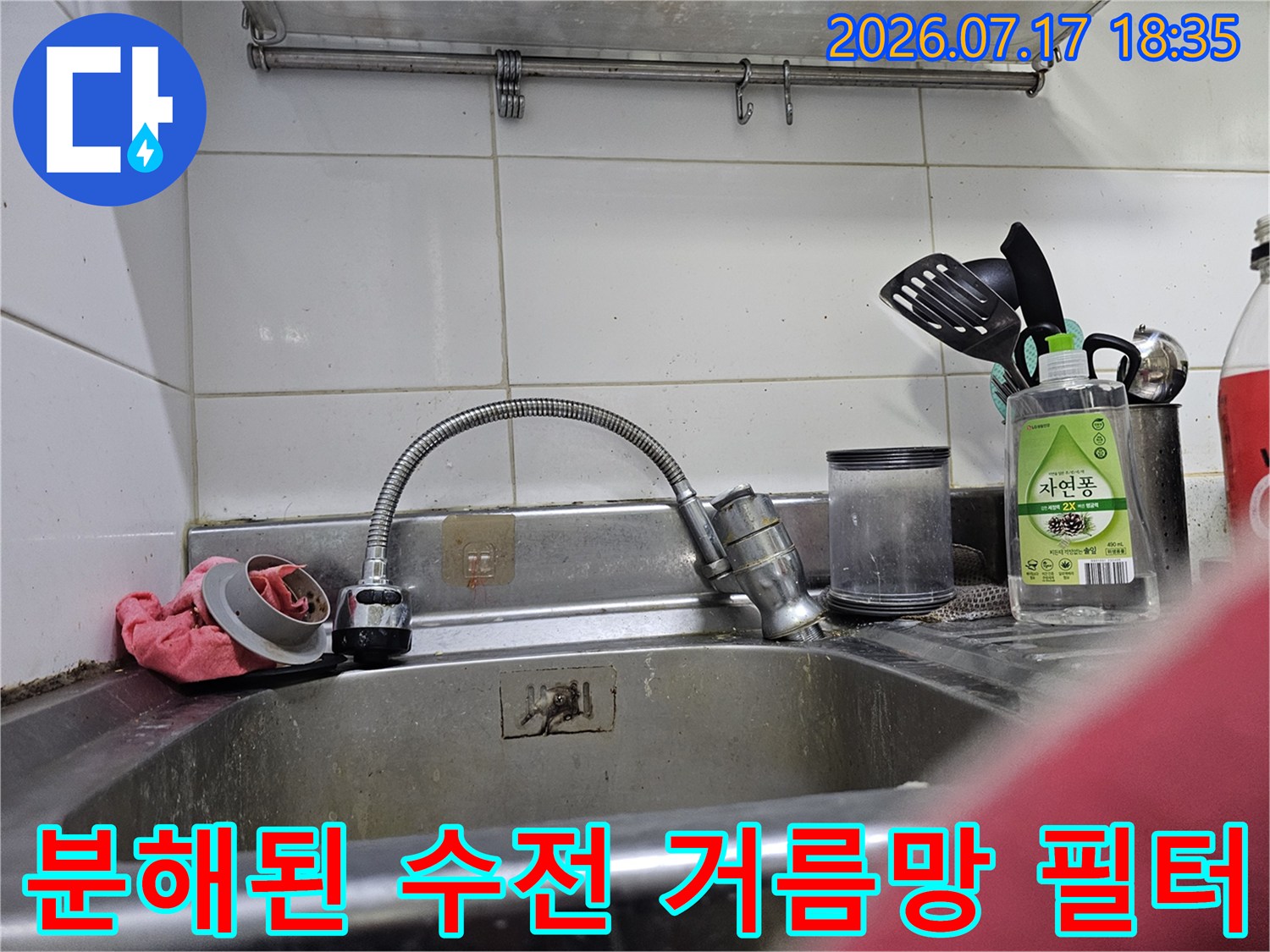 스테인리스 싱크대 위에 분리되어 놓여 있는 주방 수도꼭지용 금속제 거름망 부품