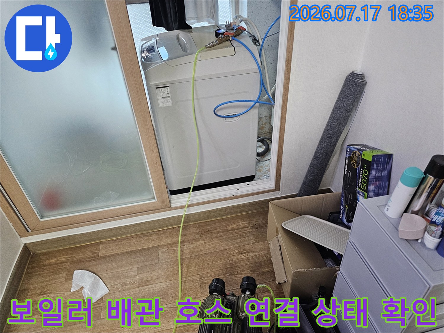 흰색 보일러 위에 파란색 수도 호스가 얽혀 있는-배관 점검 사진