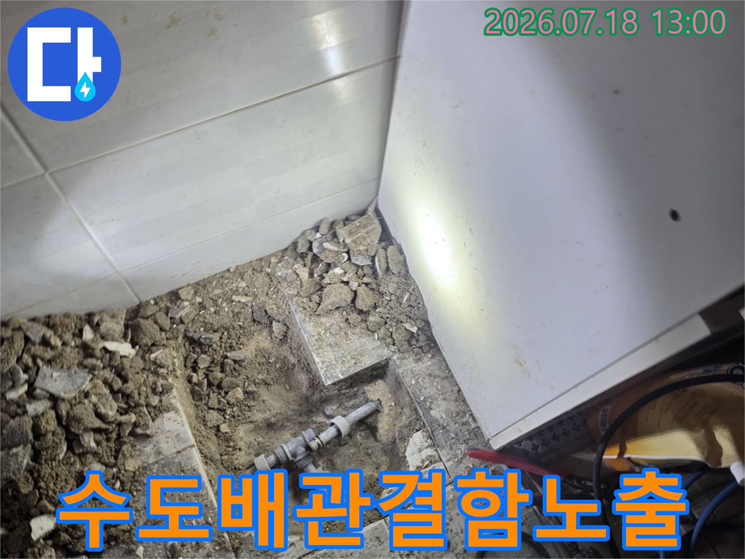 바닥 타일을 제거하고 파내어 드러난 금속 수도 배관 연결부-누수 원인 지점