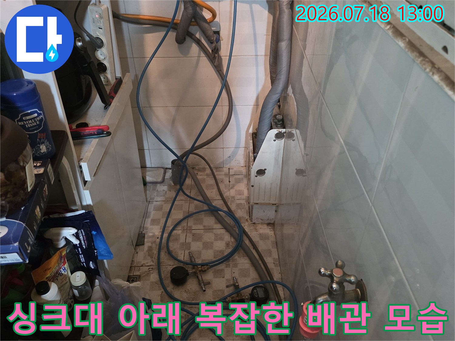 주방 싱크대 하부장에 연결된 파란색과 검은색 수도 배관-밸브 장치들