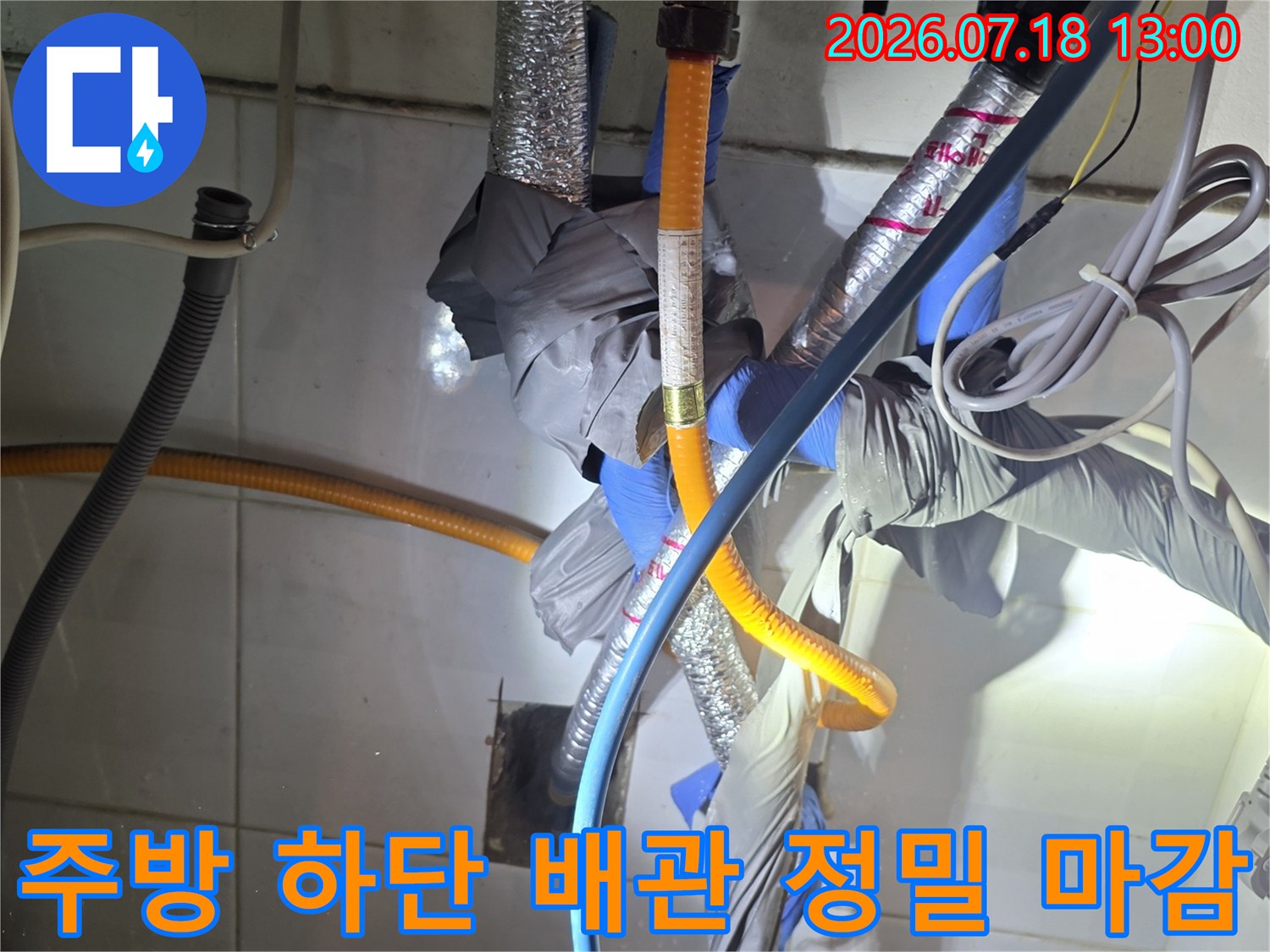 파란색 호스와 은색-노란색의 보호재가 씌워진 수도 배관들이 복잡하게 연결된 모습