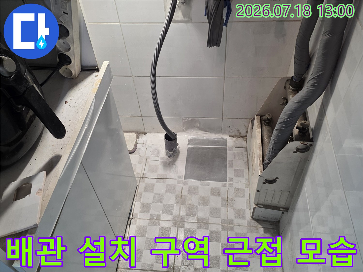 회색 보온재 관과 노란색 호스가 얽혀 타일 벽면에 고정된 사진
