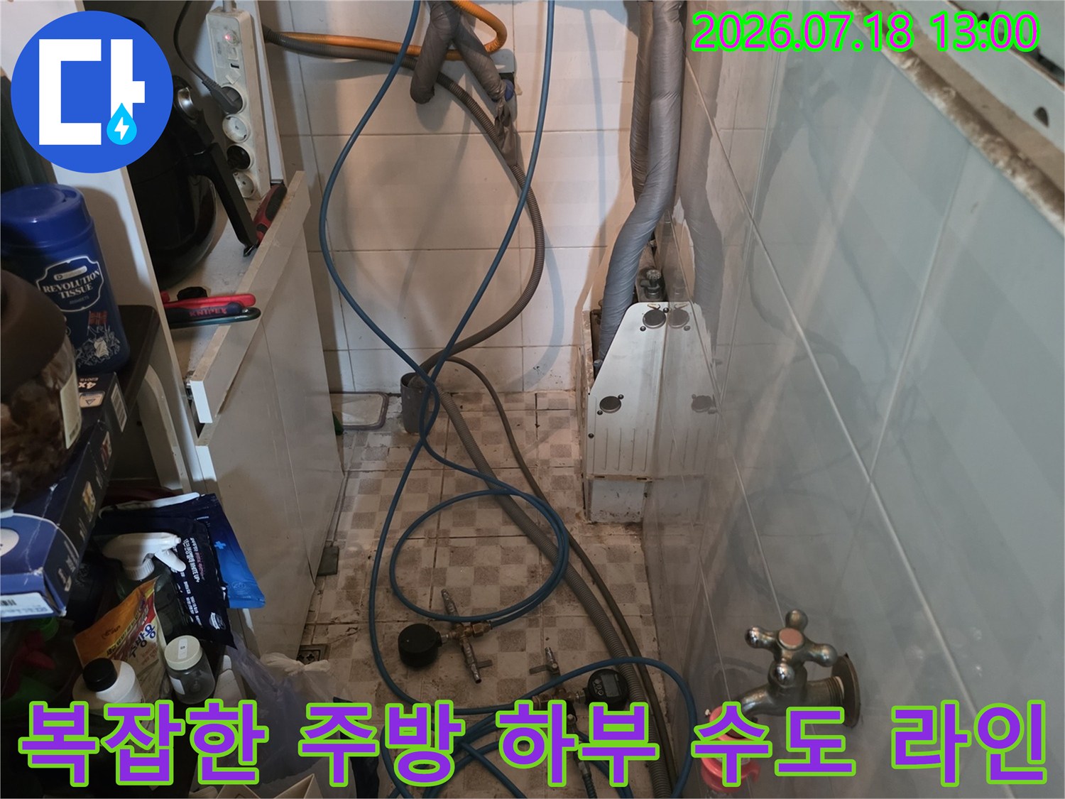 흰색 벽면을 배경으로 설치된 수도 밸브와 파란색 플라스틱 호스들