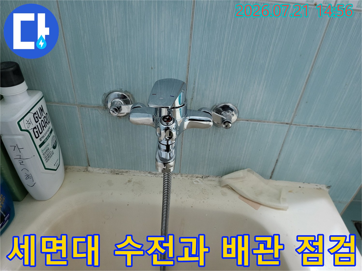 욕실 세면대 위에 설치된 크롬 소재의 수도 수전과 연결된 자바라 호스