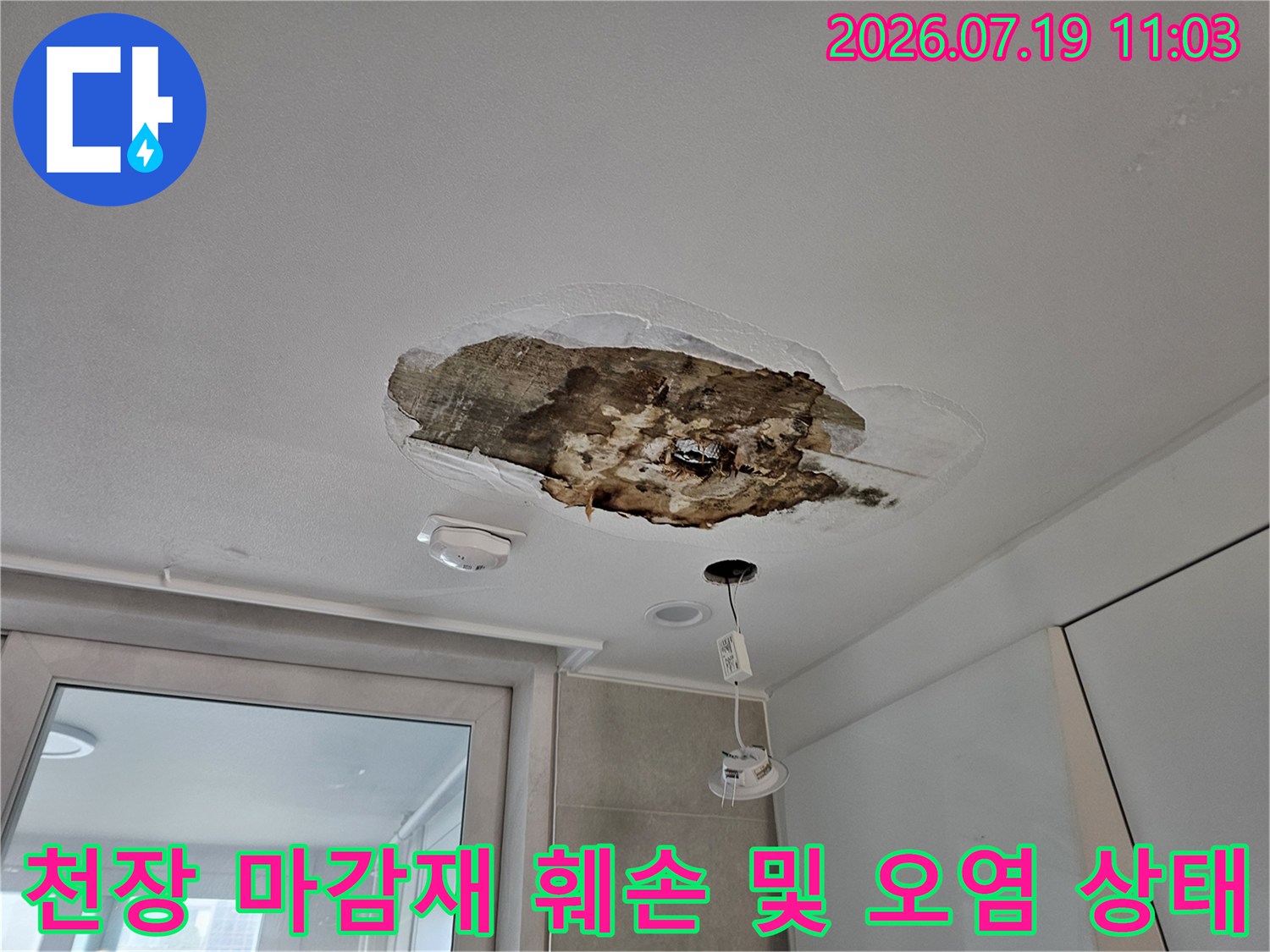 주방 천장의 석고보드가 뜯겨나가 내부의 갈색 오염물과 단열재가 드러난 모습