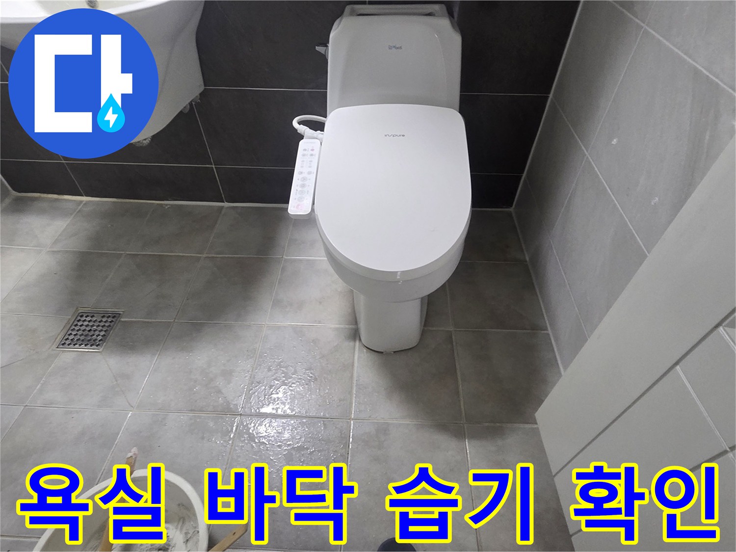 변기와 세면대 주변의 젖은 바닥 타일 상태를 찍은 사진 - 누수 진단 중