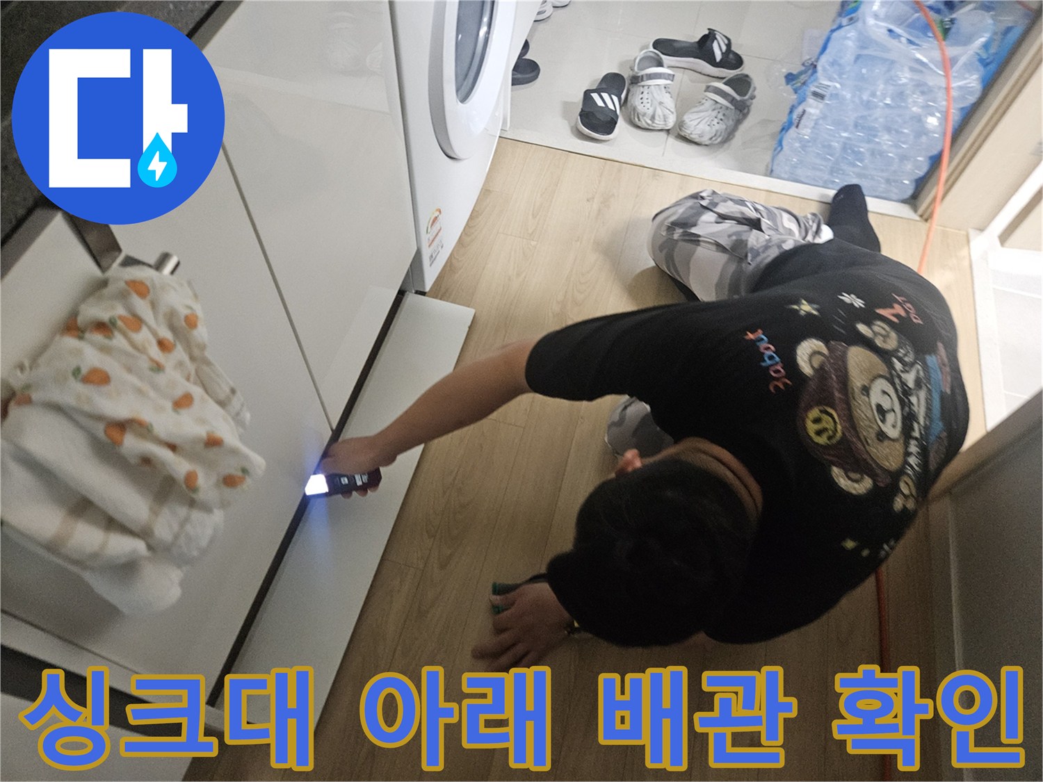 손전등-불빛으로-싱크대-하부-배관-틈새를-살피는-작업자