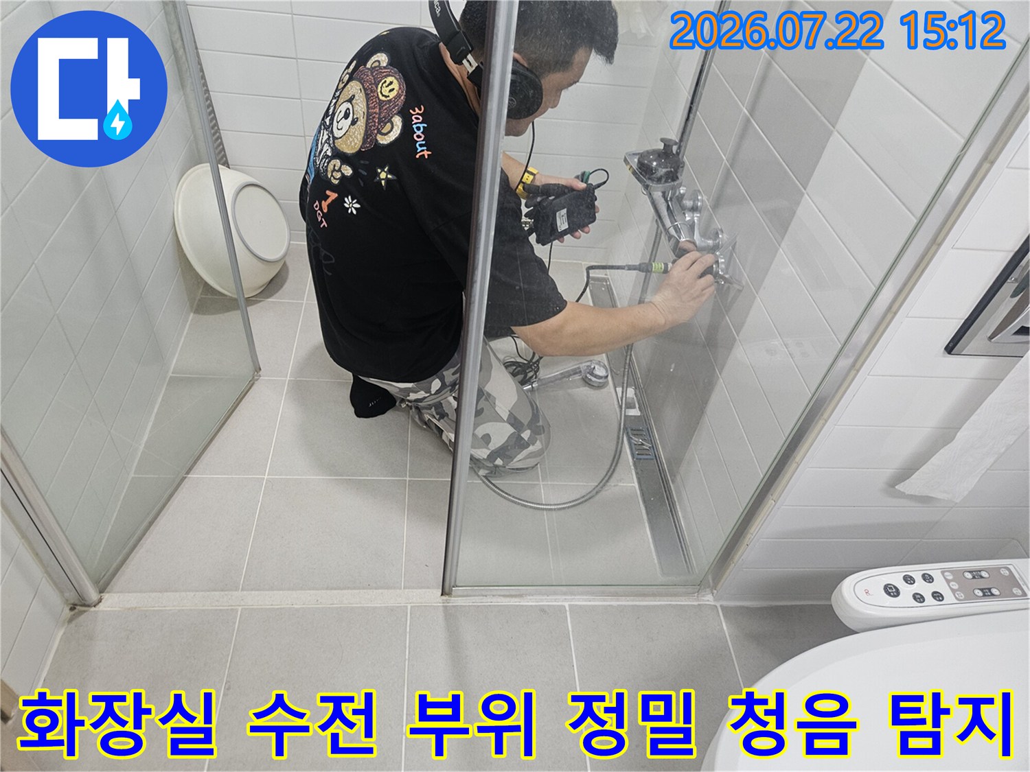 욕실 내 샤워기 수전 주변 배관에 누수 탐지 센서를 대고 소리를 확인하는 작업자의 모습