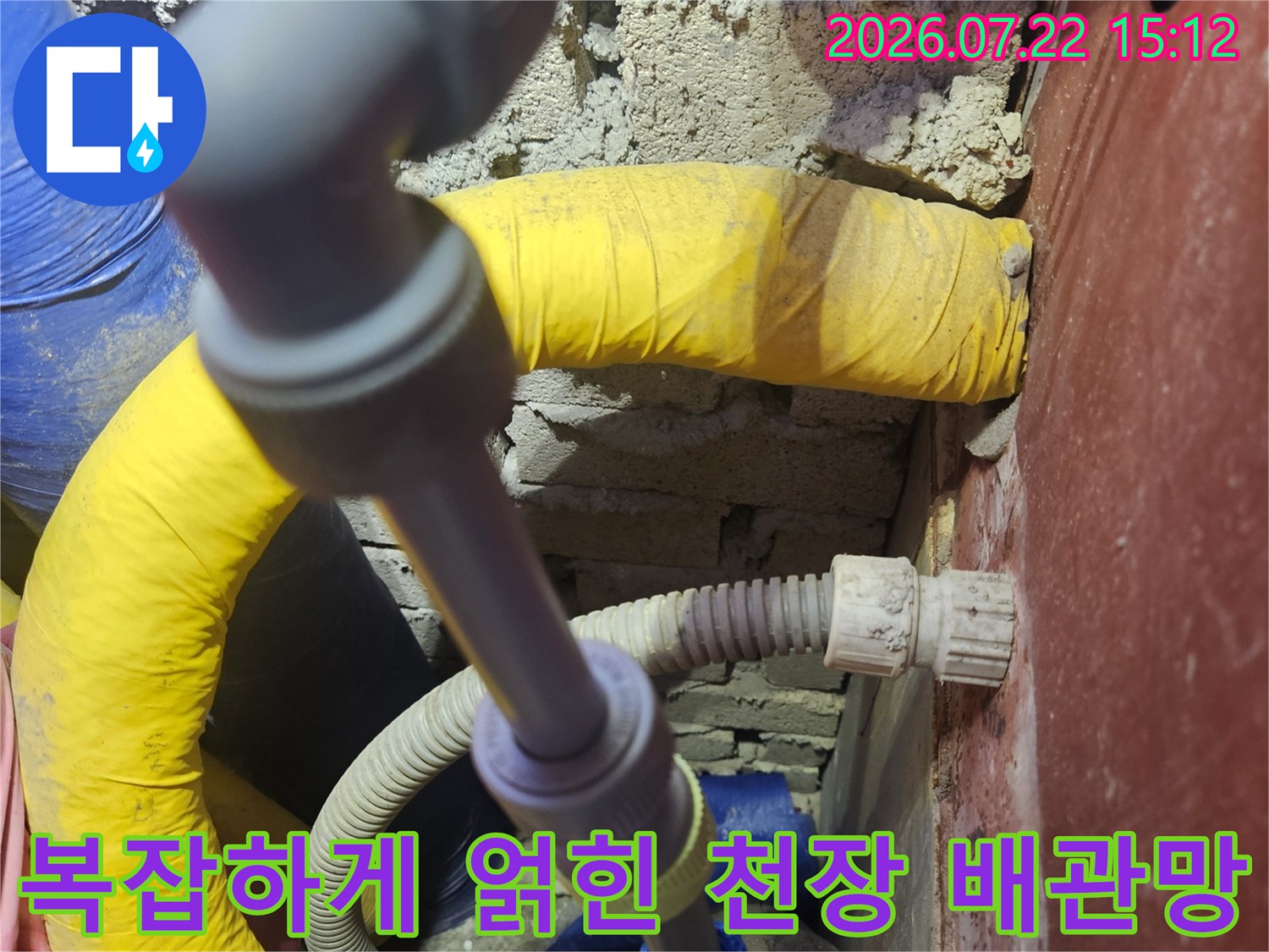 회색 연결 커넥터와 노란색 보온재 배관이 함께 설치된 화장실 천장 내부의 모습