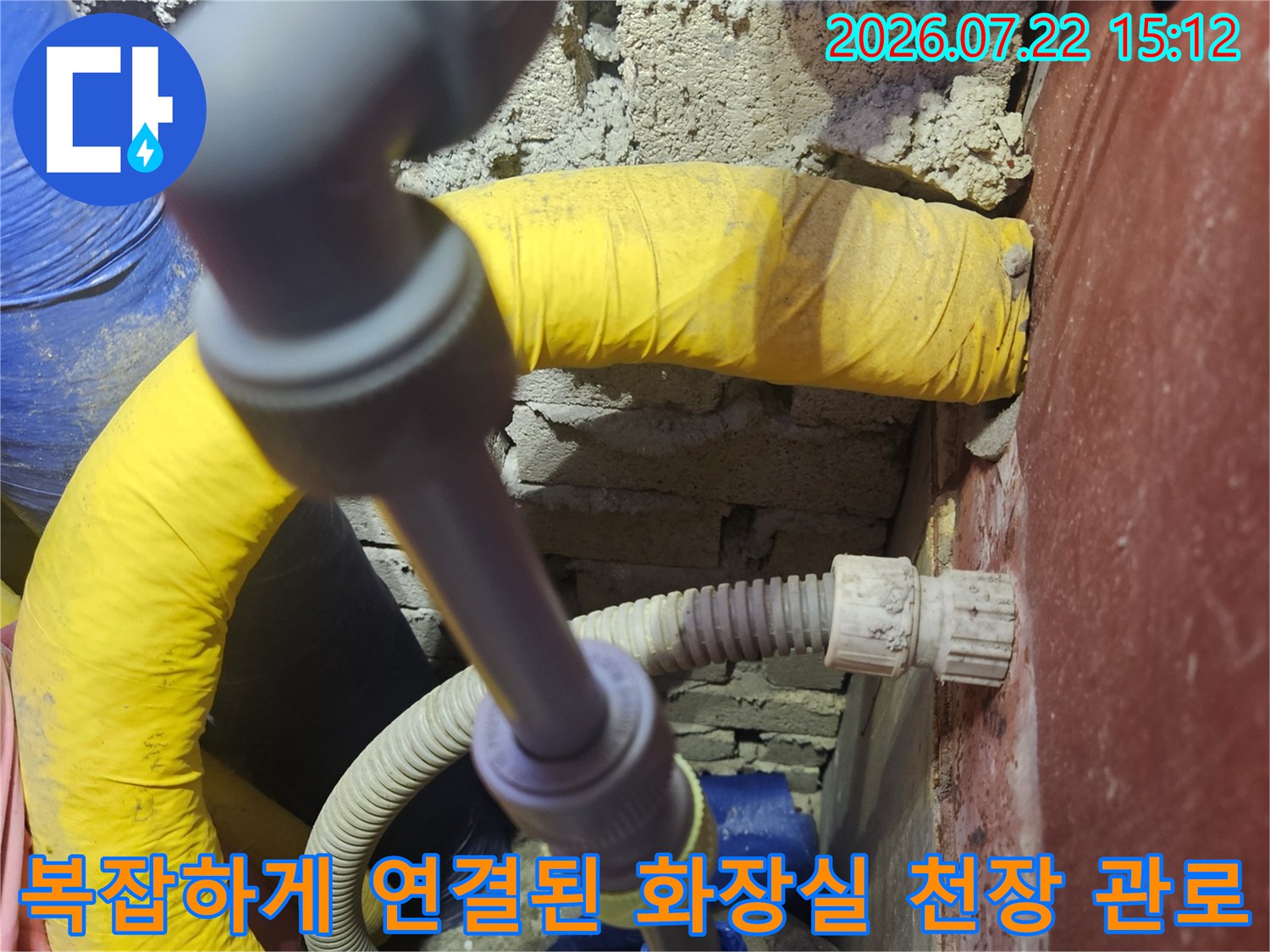 회색-플라스틱-연결재와-노란색-단열재가-감싸진-배관이-교차하는-천장-내부-전경