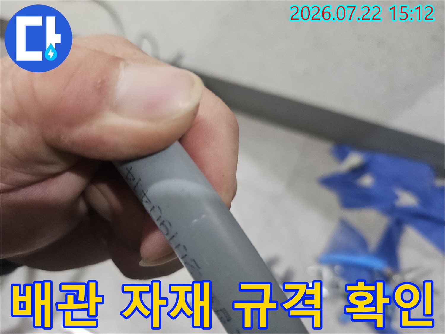 회색빛의 매끄러운 수도 배관을 손으로 잡고 세밀하게 관찰하는 사진