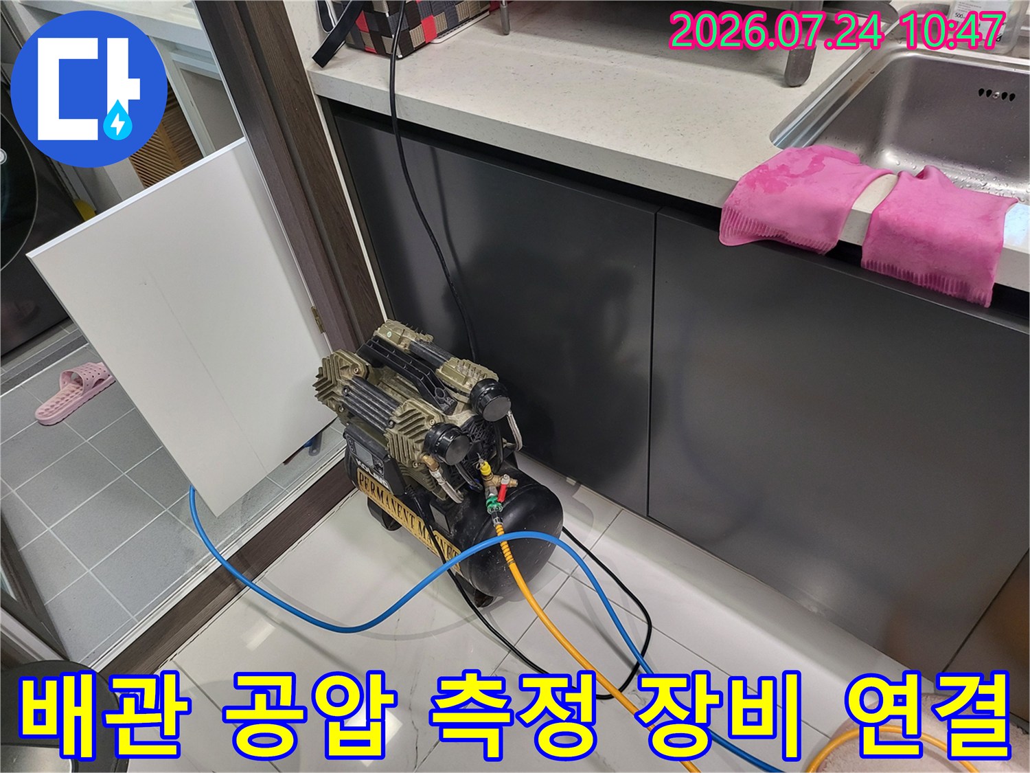 호스와 압력계가 연결된 상태로 싱크대 하단 배관을 정밀하게 테스트하는 모습