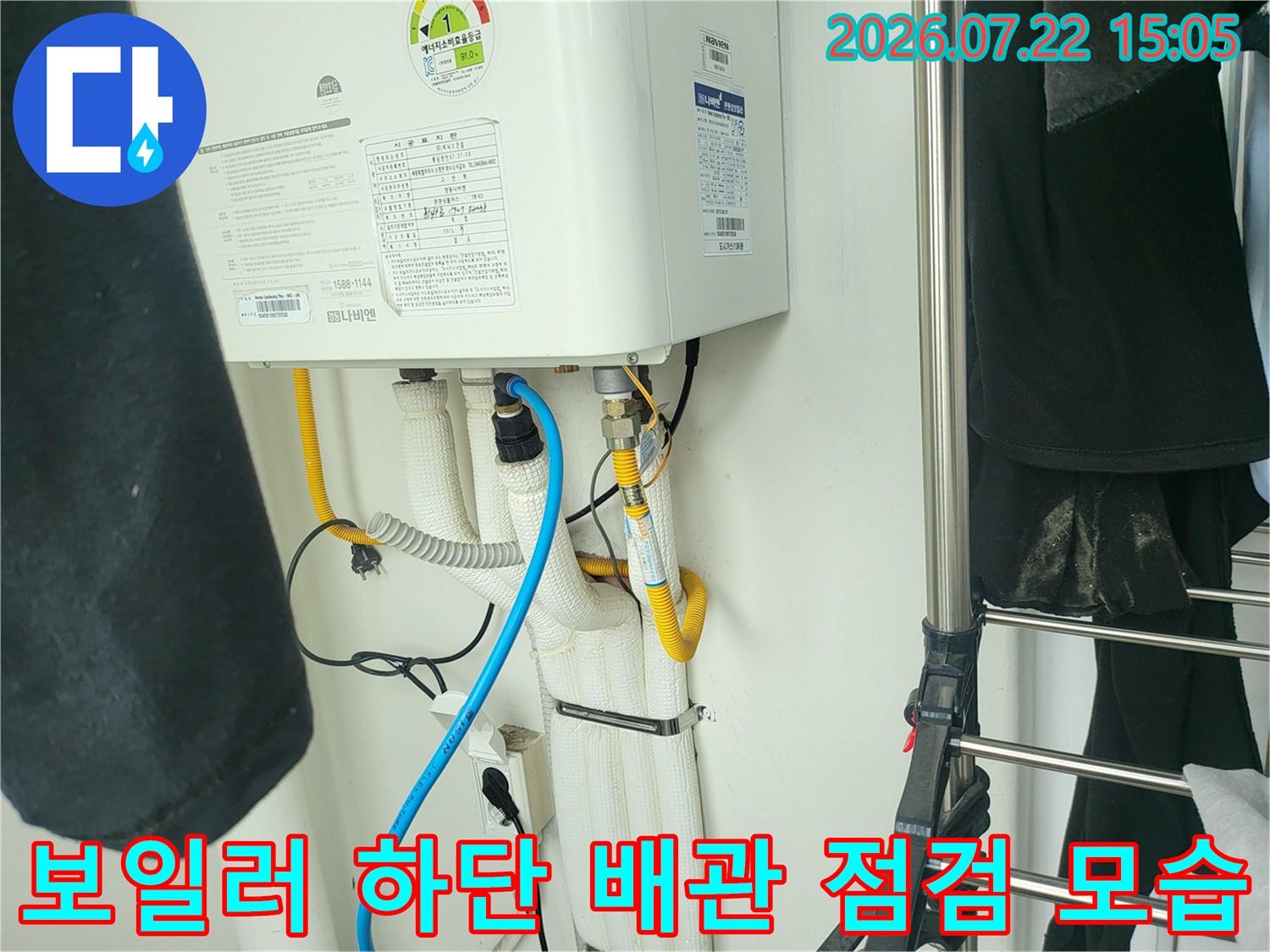 흰색 보온재로 감싸진 보일러 하단 배관과 파란색 진단 호스가 연결된 상태