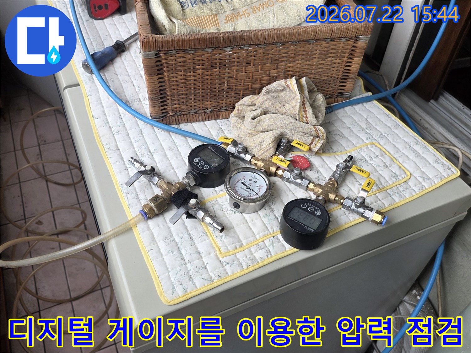 파란색 호스가 연결된 디지털 누수 탐지기가 흰색 패드 위에 놓여 있는 모습-사진