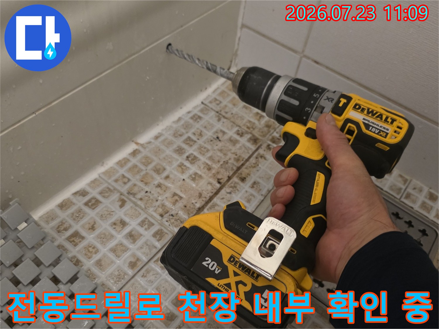 화장실 타일 벽면과 천장이 만나는 지점에 전동드릴을 대고 작업하는 사진