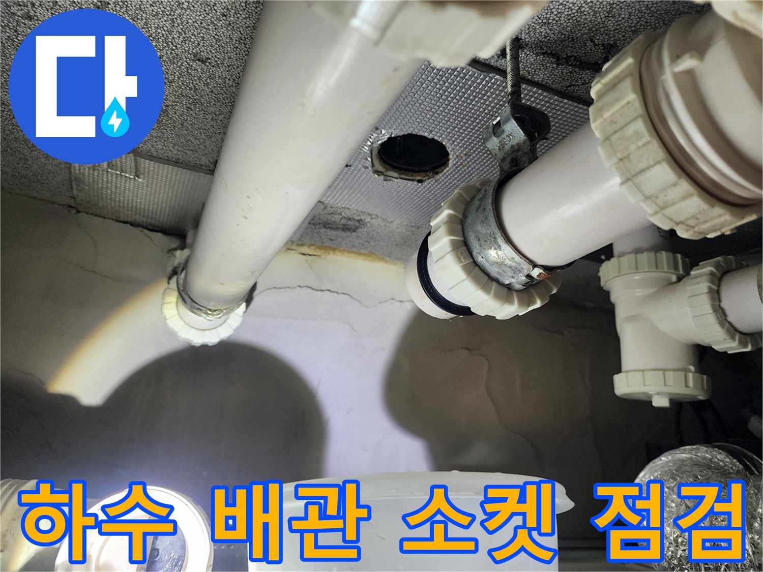 천장에 노출된 흰색 하수 배층과 연결 부속의 상태를 촬영한 사진입니다.
