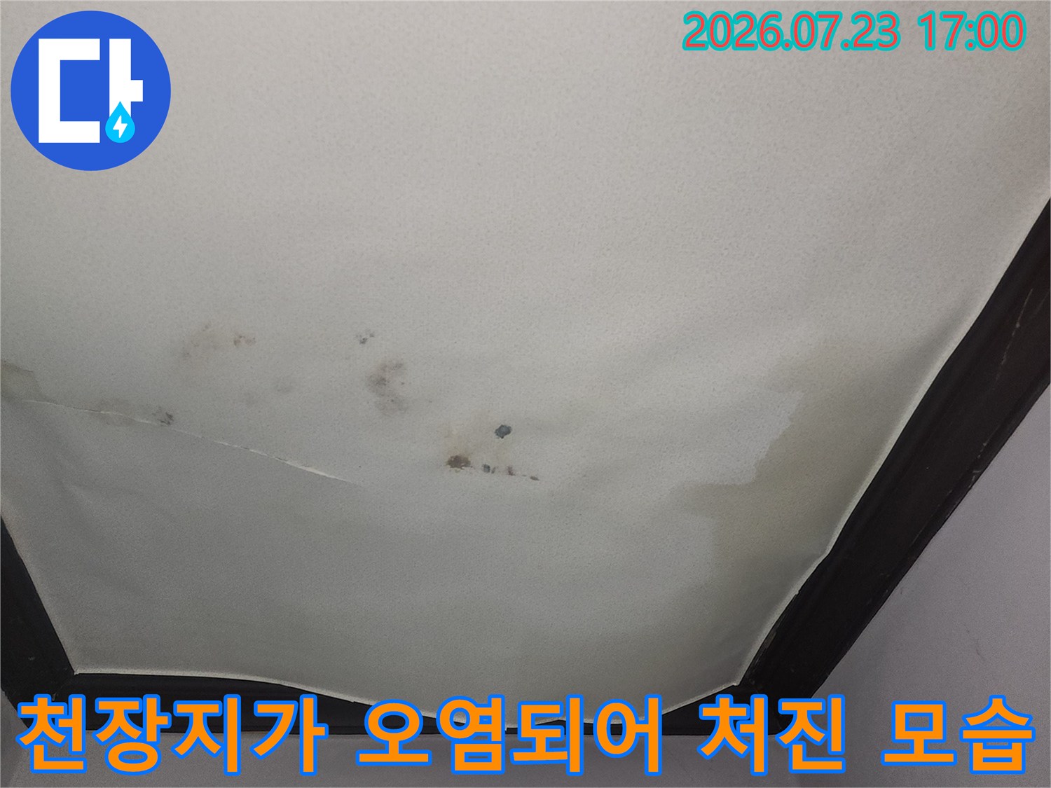 거실 천장의 하얀 벽지가 누수로 인해 변색되고 아래로 늘어진 상태