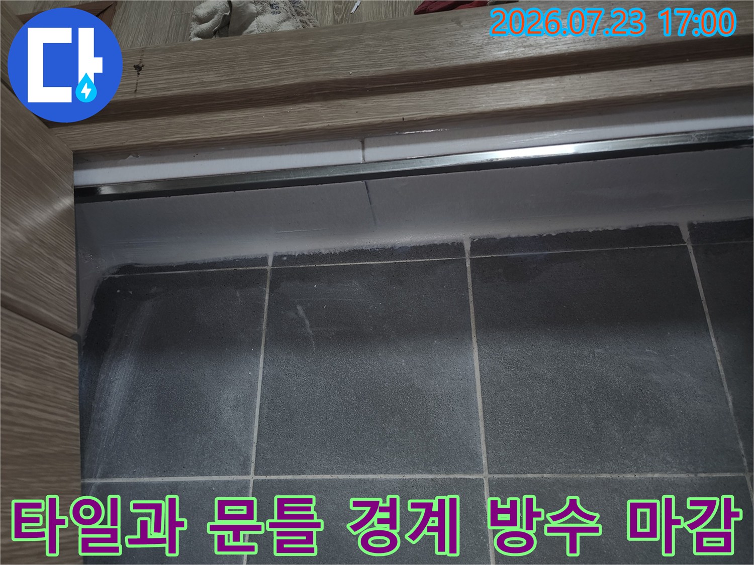 나무 소재의 욕실 문턱 아랫부분에 흰색 실리콘이 두껍고 일정하게 발라져 있는 사진