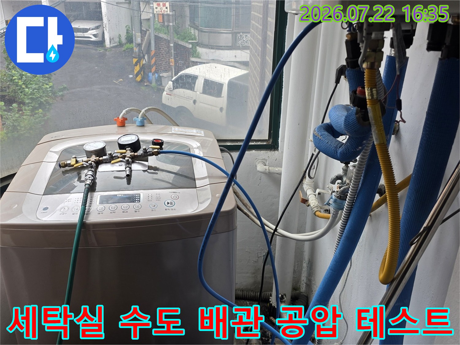 파란색 호스와 압력 게이지가 연결된 장비가 세탁기 위에 놓여 누수 검사를 진행 중인 모습