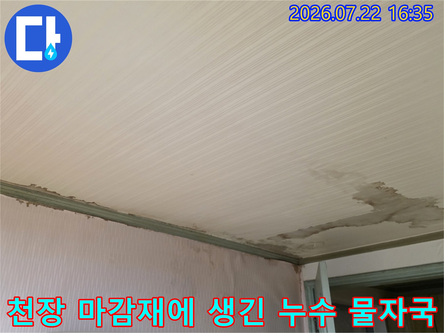 흰색 줄무늬 형태의 천장재 위에 나타난 불규칙한 모양의 갈색 누수 얼룩