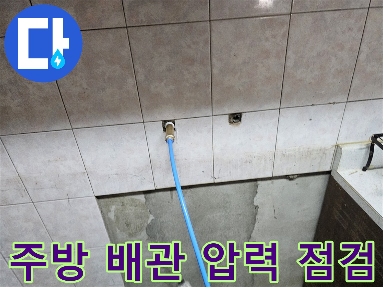 타일 벽면 배관 입구와 연결된 파란색 공압 테스트용 호스