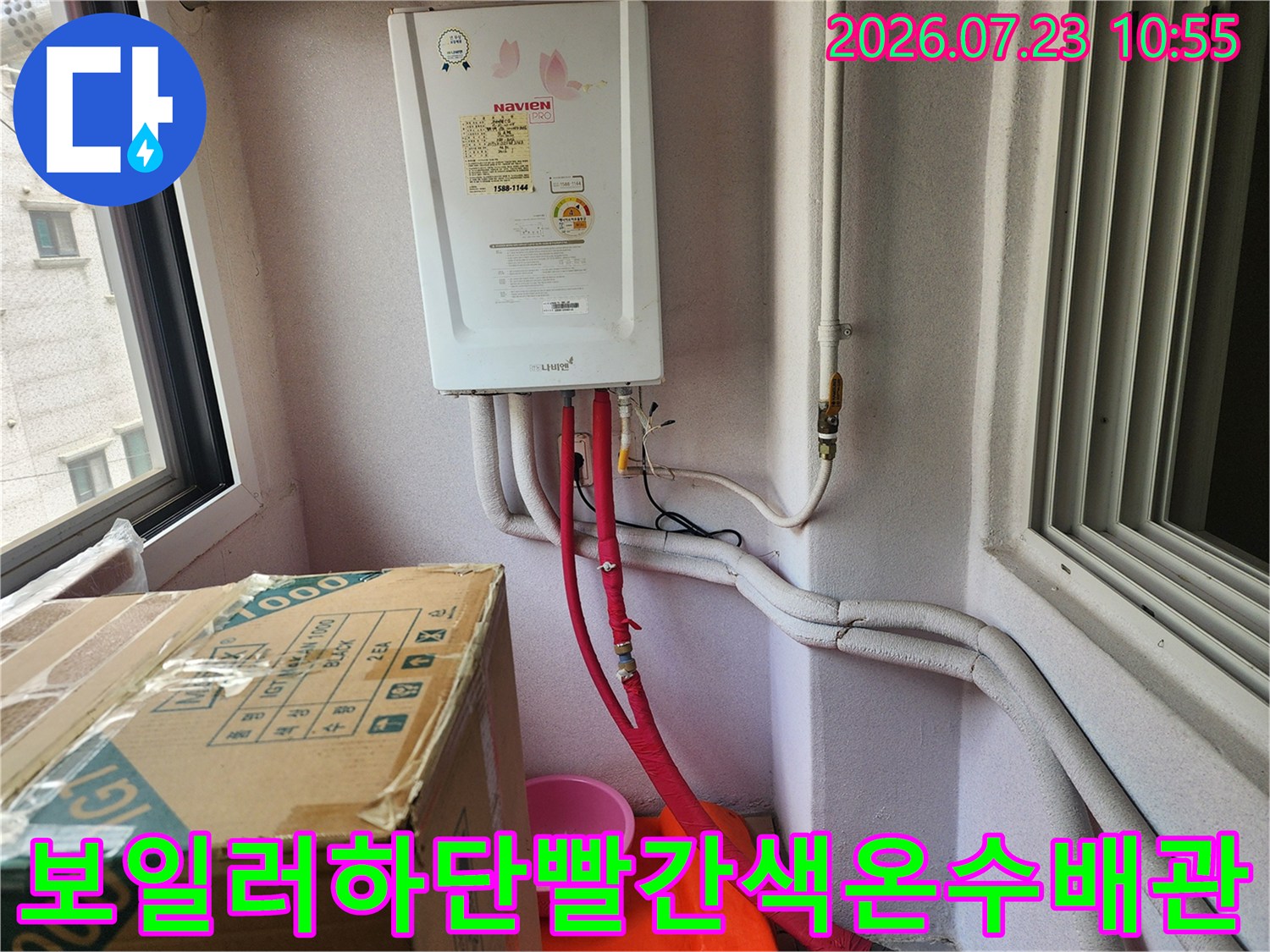 흰색 외벽에 설치된 가스보일러와 하단의 빨간색 온수 배관 연결 모습
