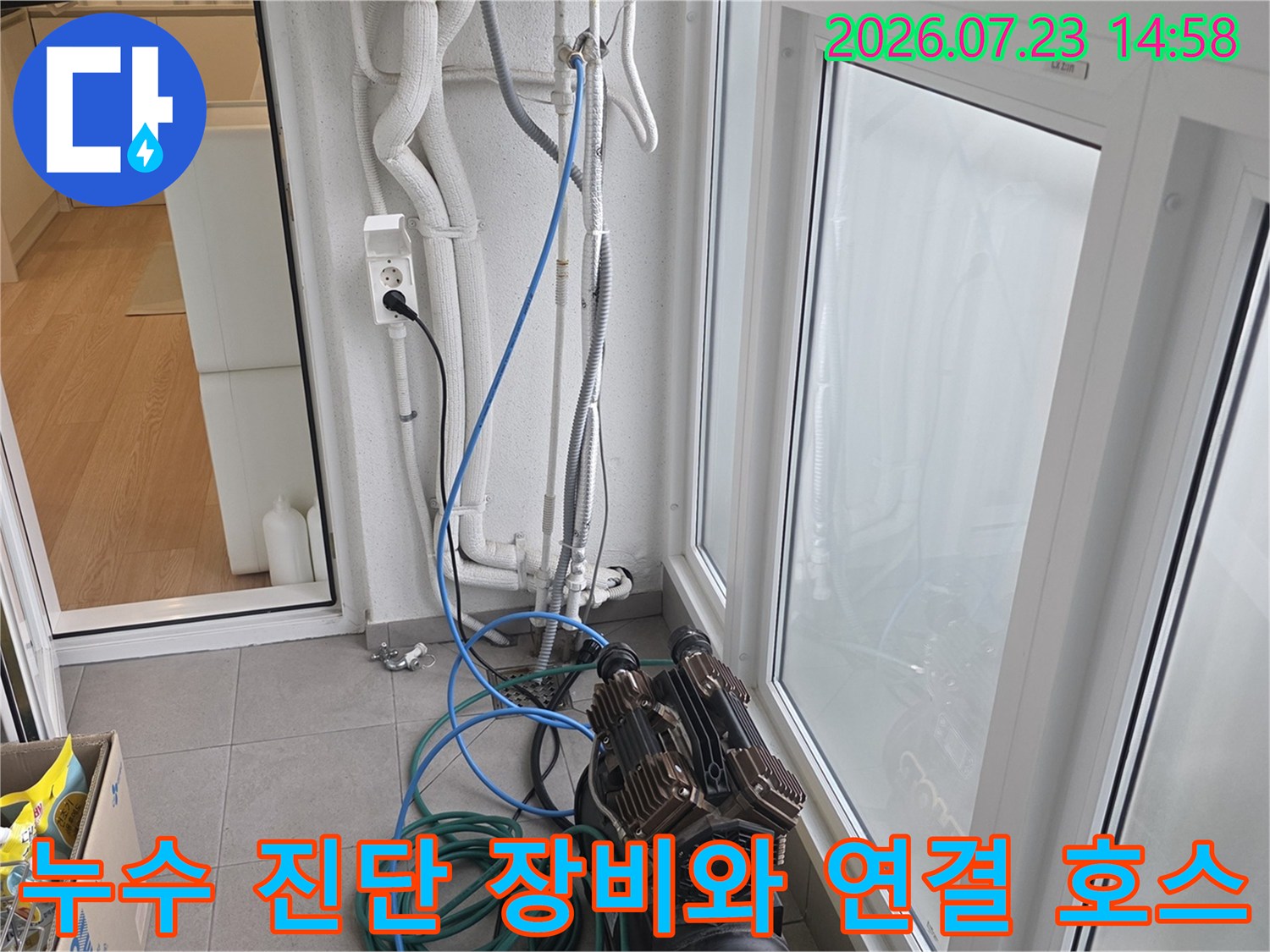 실내 바닥에 설치된 누수 탐지용 콤프레샤와 배관으로 이어진 파란색 라인