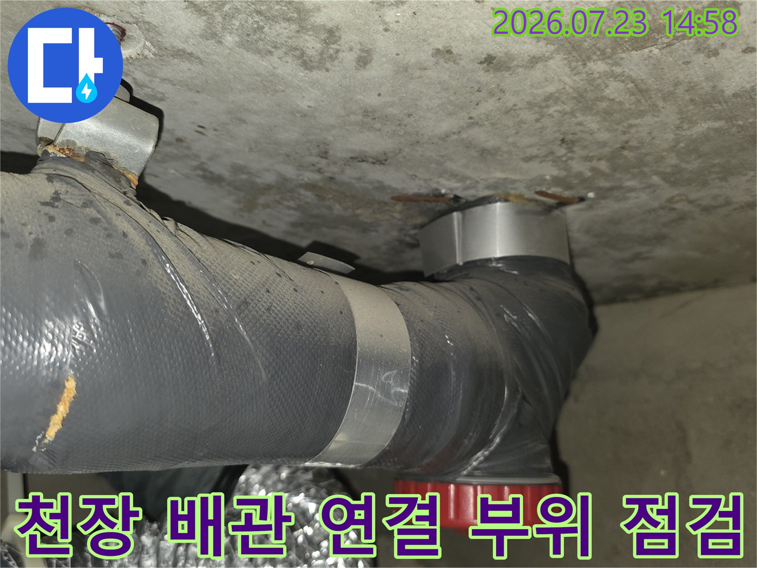 아파트 천장에서 슬라브를 관통하여 내려오는 회색 배관과 붉은색 마감 캡의 모습