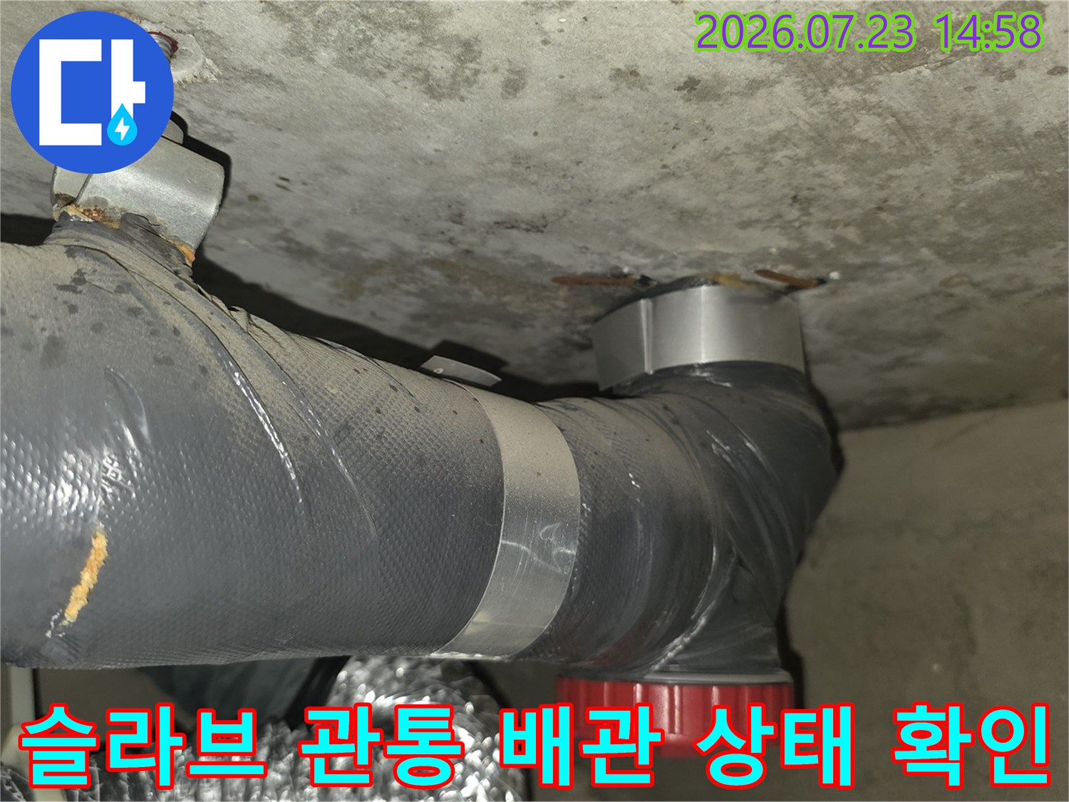 은색 테이프로 보강된 회색 배관과 천장 콘크리트 슬라브의 연결 지점 사진