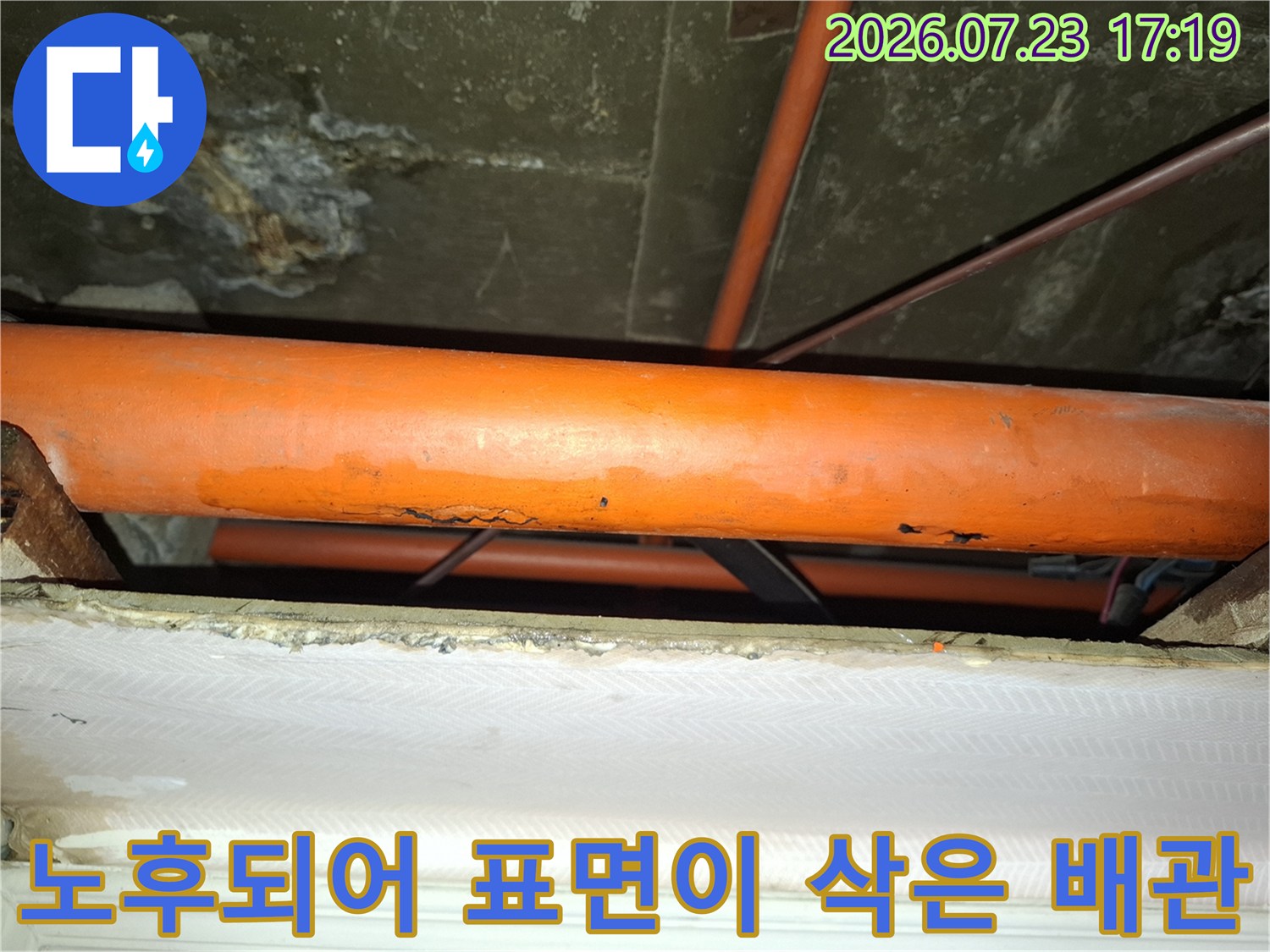 표면이 울퉁불퉁하게 부식된 오렌지색 플라스틱 계열의 배관 모습