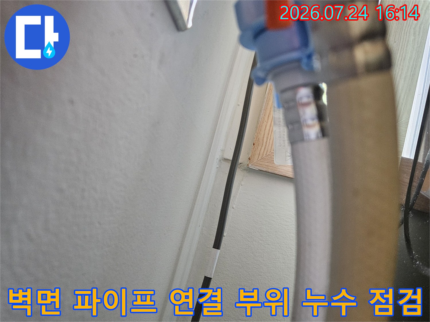 싱크대 하부 장의 배수 호스 끝단과 벽 파이프 사이의 틈새를 확인하며 보수를 준비하는 모습