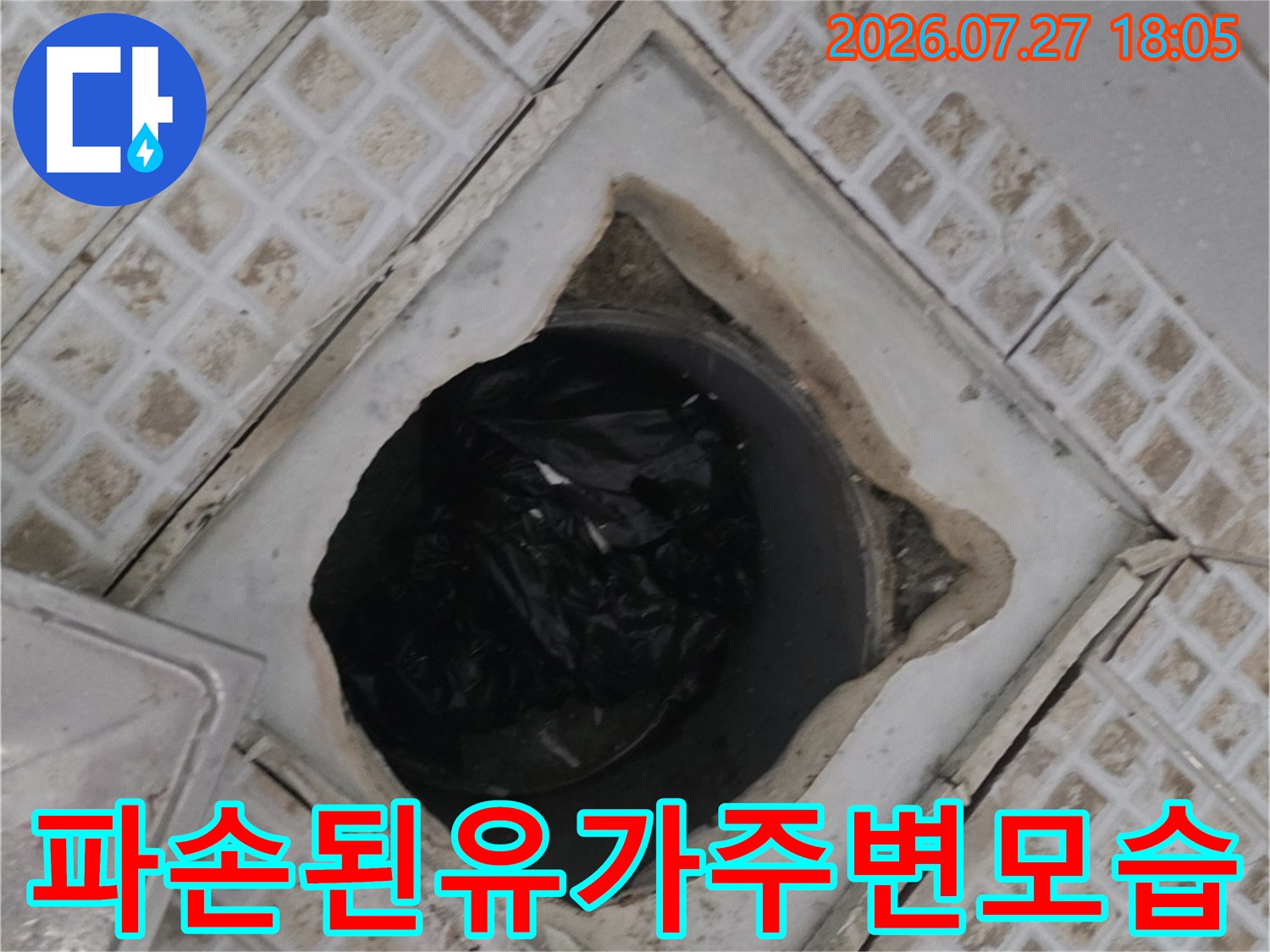 욕실 배수구 유가의 테두리 타일이 깨져 내부 배관 구조가 보이는 사진