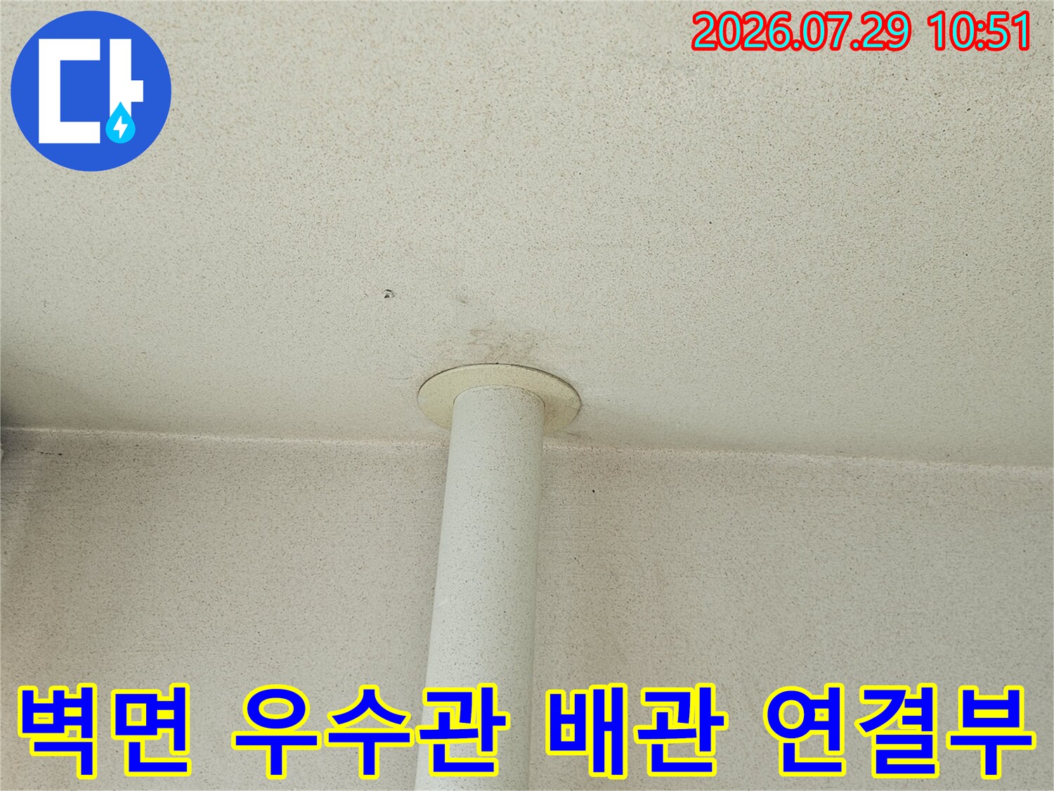 벽면에 고정된 흰색 우수관과 노출된 배관 연결 부위 상세 사진