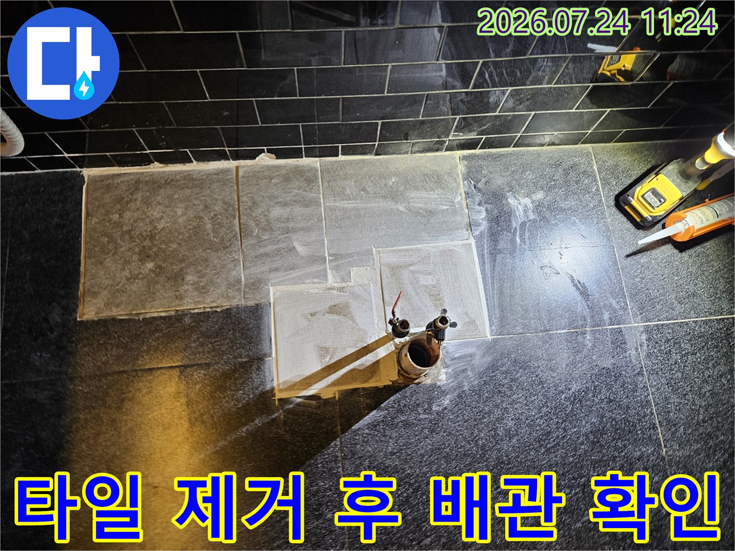 벽면 타일을 걷어내고 노출된 온수 배관의 문제 부위를 점검하는 모습