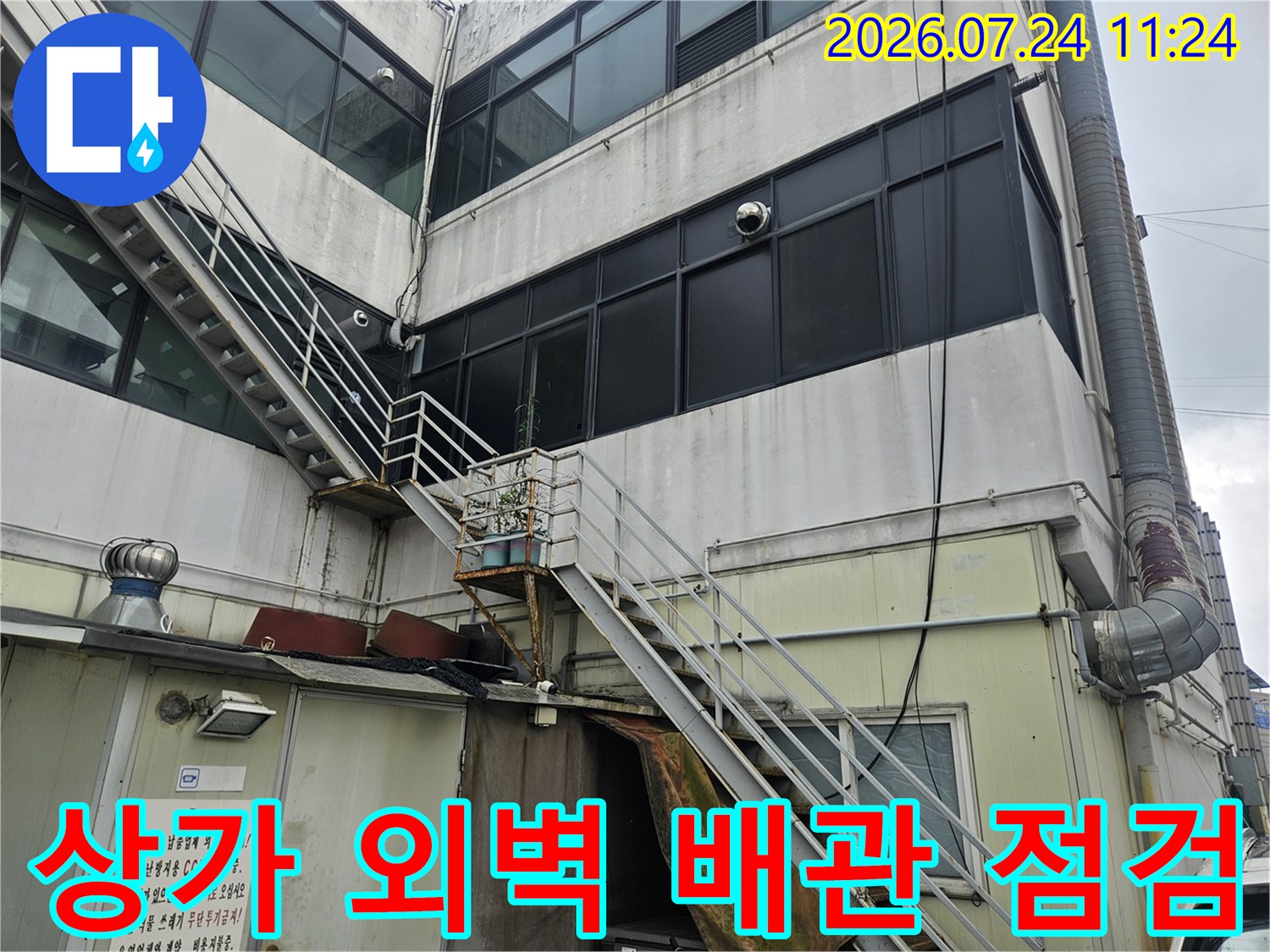 상가 건물 외벽에 설치된 노후 배관과 수동 밸브 및 계량기 시설물