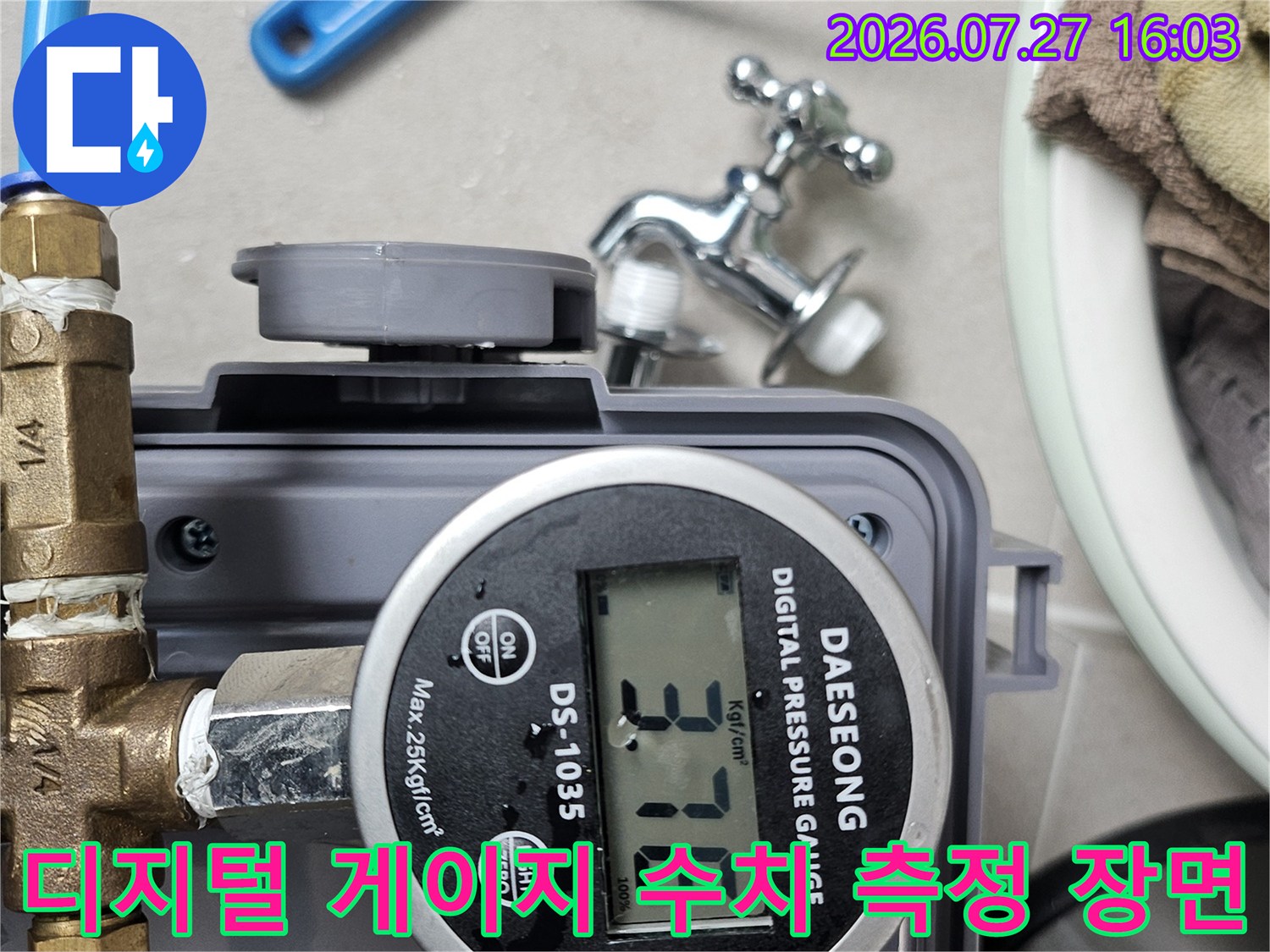 금속 밸브와 파란색 호스가 연결된 디지털 압력 게이지가 작동 중인 모습