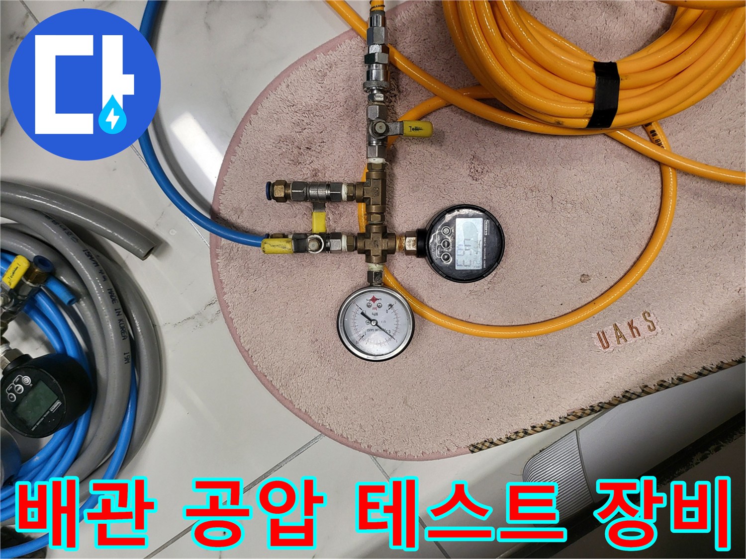 수도 배관의 기밀 상태를 확인하기 위한 압력 게이지와 호스 연결 모습