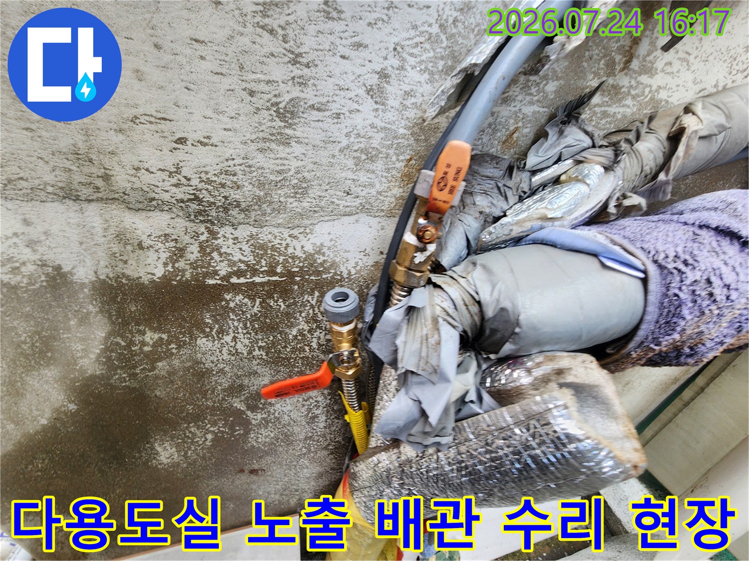 노후된 은색 단열재를 감싼 수도 배관과 밸브 연결 부위의 보수 작업 모습