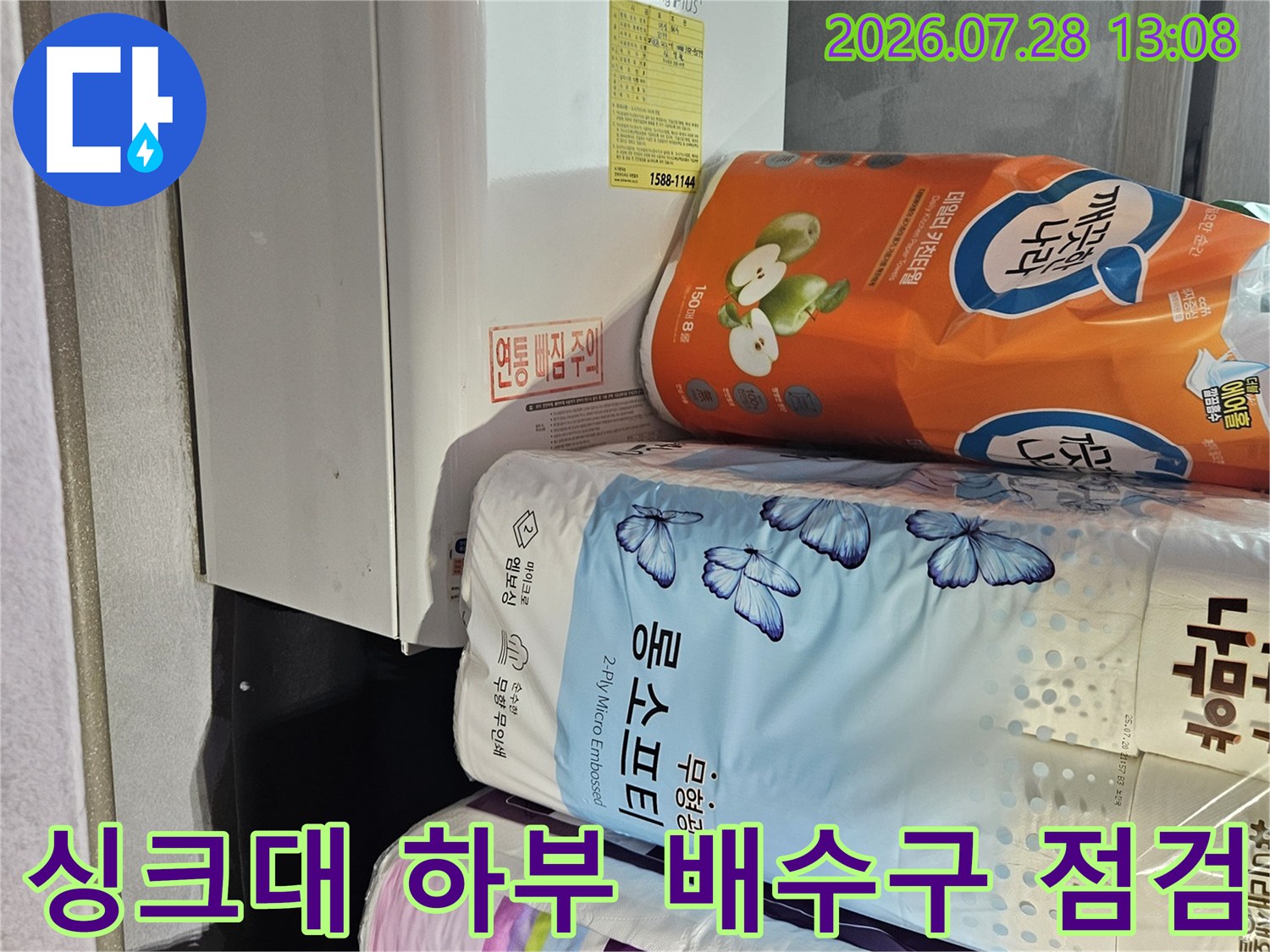싱크대 하단부에 위치한 세제와 가루세제의 상자가 놓여 있는 주방 배관 확인 현장입니다.