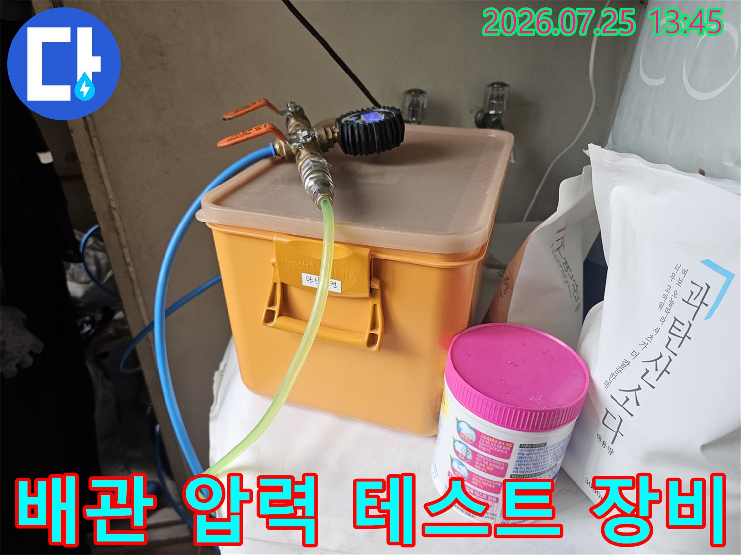 오렌지색 수납함 위 배관에 연결된 공기압 측정용 게이지와 호스